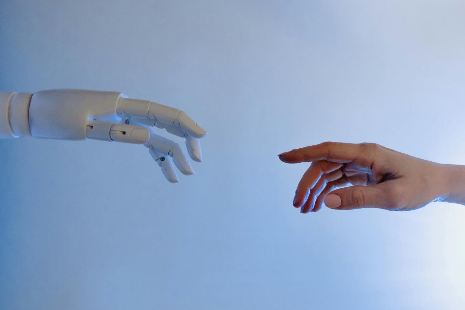 A robotic hand and a human hand reaching toward each other against a blue background
