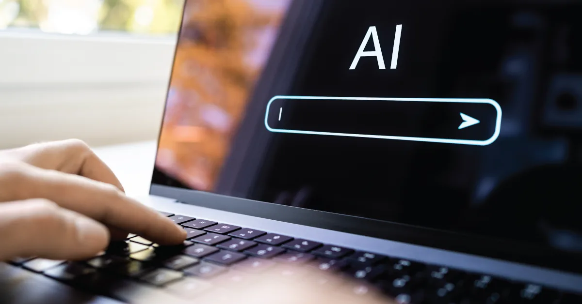 A hand typing on a laptop keyboard in front of a screen showing an AI-powered search interface