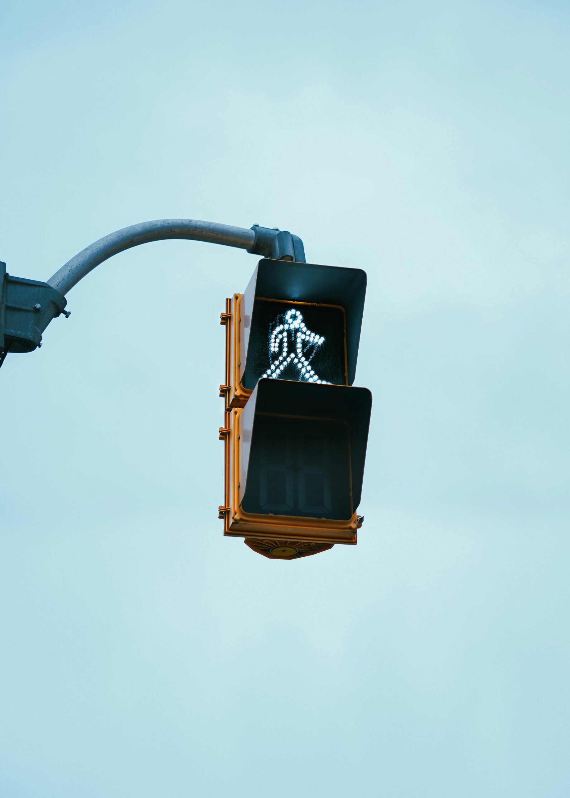 An illuminated pedestrian crossing signal against a clear sky