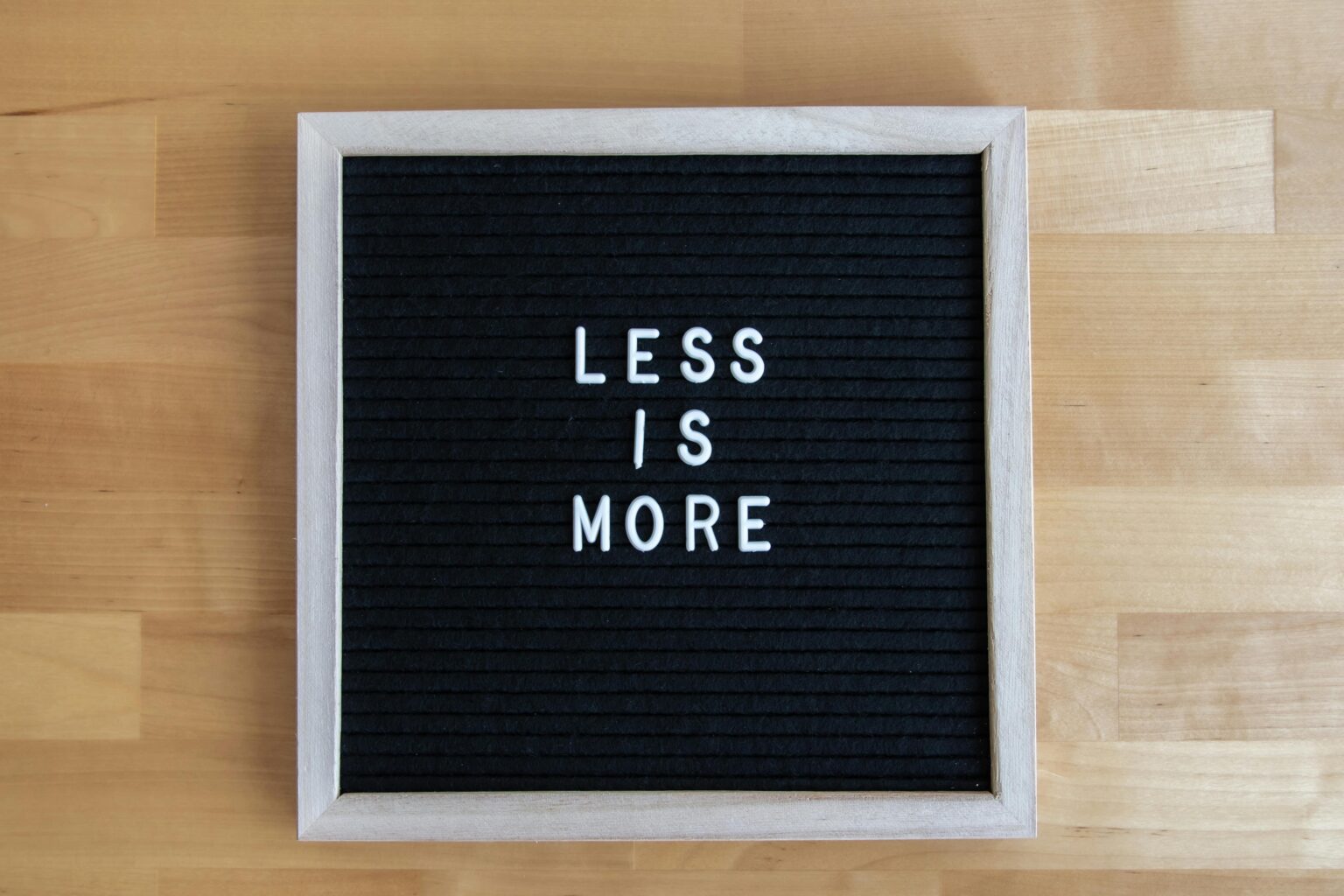 Felt letter board reading Less Is More on a wooden table